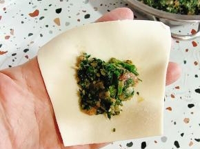 取一个饺子皮，挖一勺荠菜猪肉馅儿！