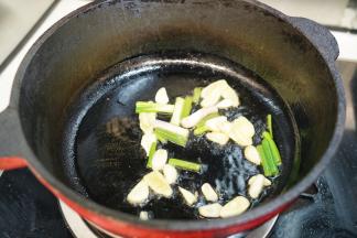 热锅后，锅里倒入20毫升植物油，放入姜片、蒜片和小葱段一起煸炒出香味