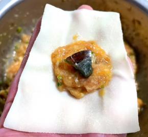 取适量馅料放在云吞皮三分之一处，皮蛋放在肉馅中间。