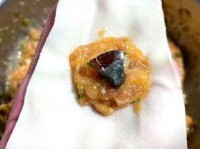 取适量馅料放在云吞皮三分之一处，皮蛋放在肉馅中间。