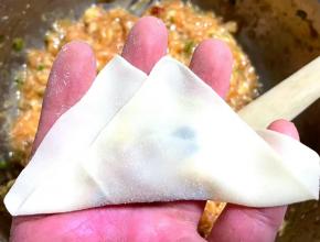 云吞皮对折，两端的云吞皮向中间聚拢。