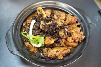 把翻拌均匀的梅菜干鸭腿放入蒸汽砂锅里，把洗净的小葱结也放入砂锅里