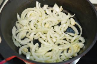 热锅后淋入橄榄油，放入洗净切丝的洋葱和切成的蒜头翻炒至洋葱变软