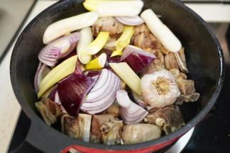 放入切块的紫洋葱、切段的京葱和带皮的蒜头一起翻炒均匀