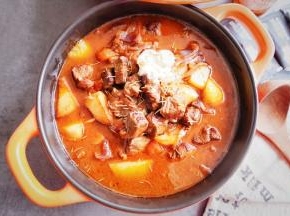 取出炖煮好的番茄牛肉，揭开锅盖，淋入奶油，撒入香草即可