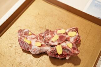 龙骨放入烤盘里，把去皮切片的姜片放在龙骨上