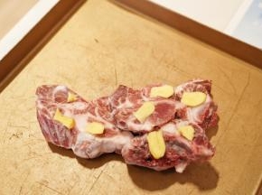 龙骨放入烤盘里，把去皮切片的姜片放在龙骨上