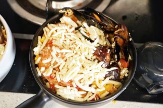 把炒好的海鲜饭放入烤碗里，在米饭上面撒入马苏里拉奶酪