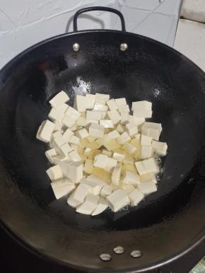 锅烧热倒入适量的油，转动锅，把锅润一下油，再把嫩豆腐切成小块，放在锅里煎！