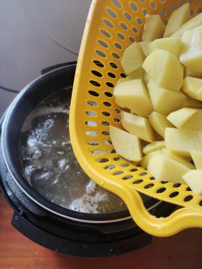 时间到，气压阀落下，打开盖子，按“开盖煮”放入土豆煮！