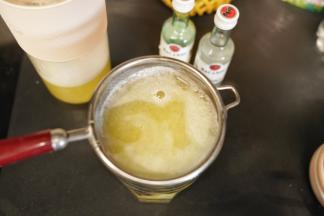 把榨好的菠萝果汁通过滤勺倒入杯中