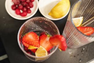 在杯里勺入30克椰果粒，柠檬洗净后切成小块放入杯里，把切好的草莓和蔓越莓鲜果也放入杯中