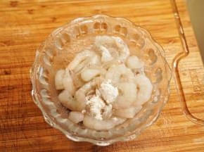 虾仁去除虾线，洗净后放入碗里，加入生粉和2克盐抓拌均匀腌制10分钟