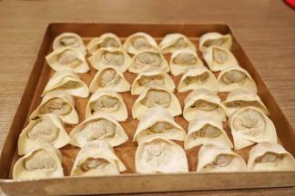 馄饨皮上下对折，捏紧封口，再左右对折捏紧即可，可以蘸水捏紧包好的馄饨放入烤盘里