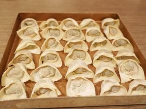 馄饨皮上下对折，捏紧封口，再左右对折捏紧即可，可以蘸水捏紧包好的馄饨放入烤盘里