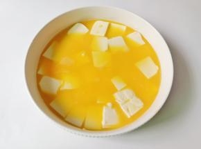 把豆腐放入碗里，倒入鸡蛋液