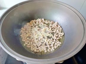 边炒到肉丁变色，放蒜炒香。