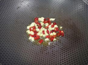 炒锅内倒适量的玉米油烧热，下入大蒜和辣椒段炒香。