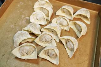 馄饨皮上下对折，捏紧封口，再左右对折捏紧即可，可以蘸水捏紧包好的馄饨放入烤盘里