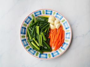 韭苗洗净切段，胡萝卜去皮切段，大蒜拍扁。