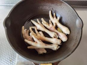 不粘锅加玉米油，下姜片大火爆香，放入凤爪，略微翻炒至表面金黄。