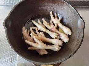 不粘锅加玉米油，下姜片大火爆香，放入凤爪，略微翻炒至表面金黄。