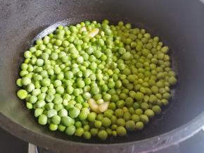 起锅热油，放入大蒜爆香，放豌豆粒炒匀，