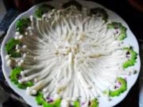 焯好的金针菇过凉水、沥干水分，摆在盘中。