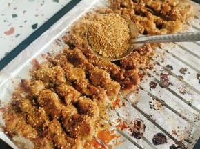 把烤盘取出来，用漏勺在肉串上撒适量的烧烤料！撒好一面，把肉串翻面，再继续均匀的撒烧烤料！