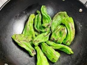锅烧热，倒少许的油，油热后把辣椒倒入锅中，开小火慢慢的煎！边煎边用铲子轻轻的按压，这样可以快速的起虎皮！切记不要开大火，要不然容易把辣椒煎糊了！一直把辣椒煎成这样的虎皮状就可以了！把辣椒盛出来备用！