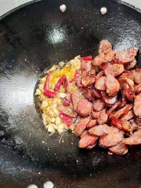 把熏腊肠扒拉到一边，放入生姜，干辣椒，花椒，蒜瓣爆香，再放入适量的生抽翻炒均匀！