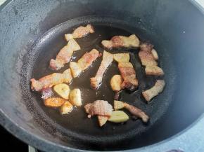 起锅加少许油，爆香大蒜，加入腊肉炒至金黄，