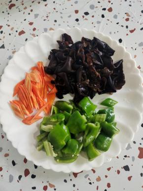 准备好配菜:青椒去蒂洗净切成小块，胡萝卜去皮洗净切成片，木耳提前泡发好，清洗干净备用！