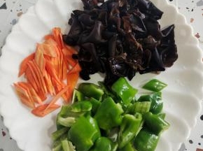 准备好配菜:青椒去蒂洗净切成小块，胡萝卜去皮洗净切成片，木耳提前泡发好，清洗干净备用！