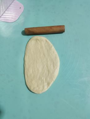 取出一个松弛好的面团擀开，擀成牛舌状。