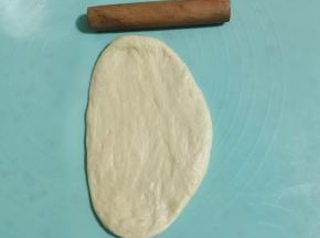 取出一个松弛好的面团擀开，擀成牛舌状。