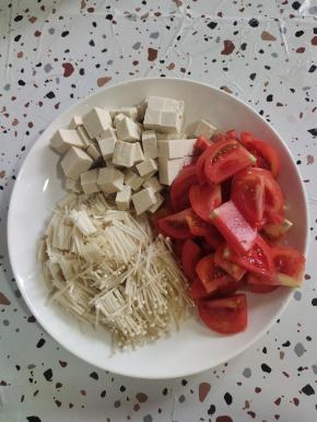 西红柿切成片，豆腐切成小块，金针菇去掉根部清洗干净切成段备用！