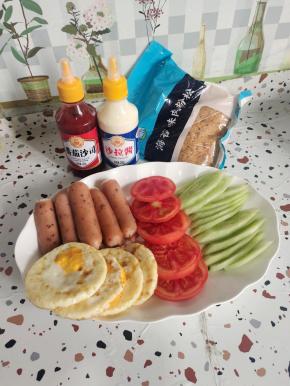 准备好今天做脆皮烤肠三明治的材料:
黄瓜削皮已经，斜切成片，黑椒脆皮烤肠对半切开，西红柿选择硬一点的西红柿切成片，鸡蛋提前煎熟备用！(我的鸡蛋直接用烤箱烤的少油健康！)番茄酱，沙拉酱，海苔肉松适量！