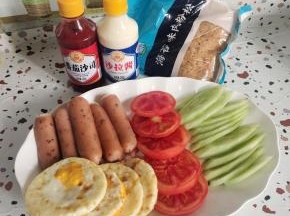 准备好今天做脆皮烤肠三明治的材料:
黄瓜削皮已经，斜切成片，黑椒脆皮烤肠对半切开，西红柿选择硬一点的西红柿切成片，鸡蛋提前煎熟备用！(我的鸡蛋直接用烤箱烤的少油健康！)番茄酱，沙拉酱，海苔肉松适量！