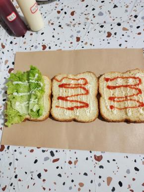 第一片面包上放入两片嫩生菜，然后挤上适量的沙拉酱！