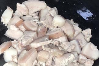 将锅清洗干净，烧干水分，倒入五花肉煸炒出油至表面金黄