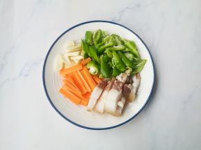 腊肉切片，辣椒切滚刀块，大蒜、胡萝卜切片。