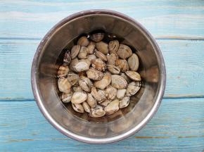 花甲放入盆中冲洗干净，扣子盘子上下颠簸几下，加入40度的温水没过花甲，