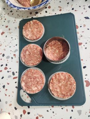 烤盘上放一张烤肉纸，饺子皮模具放在烤肉纸上，挖两勺腌制好的肉馅儿。按压成圆饼状！