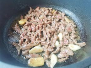 锅中热油，爆香大蒜，加入牛肉炒至变色捞出备用。