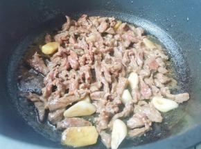 锅中热油，爆香大蒜，加入牛肉炒至变色捞出备用。