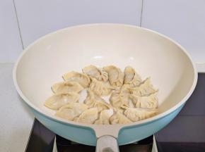 锅中喷油摆入饺子。