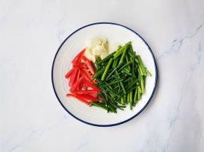 韭苗洗净切段，红椒切条，大蒜切片。