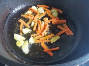 热锅倒油，爆香大蒜，加入胡萝卜炒熟，