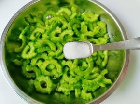 加一勺盐，用手抓拌均匀腌制五分钟，五分钟后用手把苦瓜挤干，再用清水多冲洗几遍，沥干水分